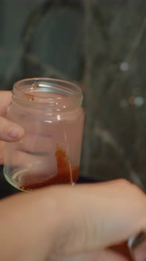 Vidéo verticale Remplir soigneusement des bocaux en verre avec de la confiture de prunes fraîchement bouillie dans une cuisine confortable