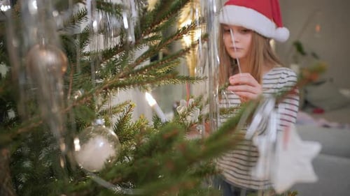 little girl is helping decorate the Christmas tree