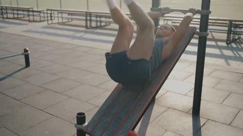 Young Man Exercising Outdoors on Fitness Equipment at Public Park