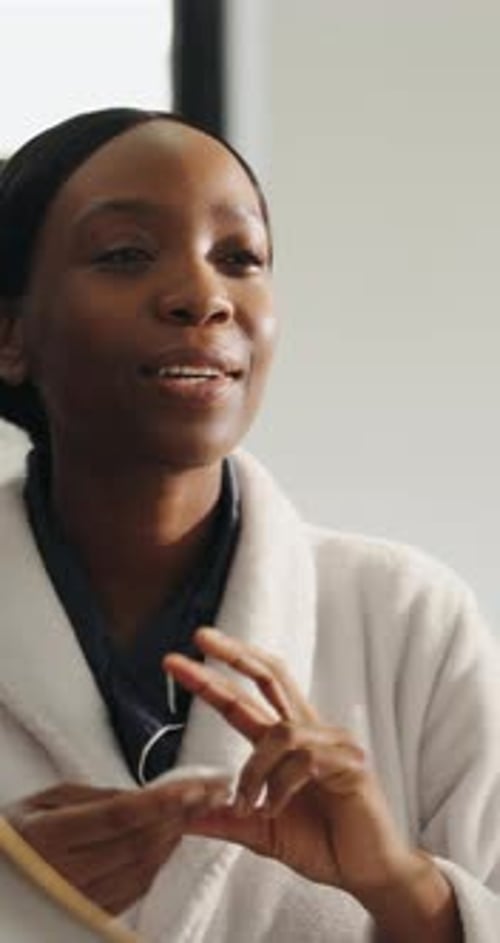 Woman in Robe Cleansing Face With Cotton Pad