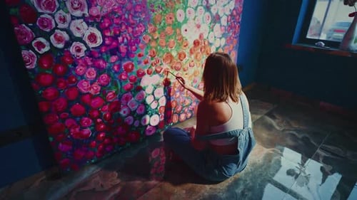 Künstlerin malt bunte Rosen auf großer Leinwand