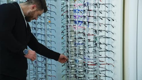 Elegant young man looking for modern eyeglasses.