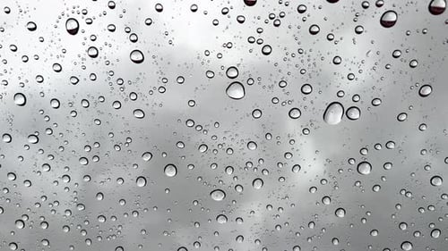 Vertical wallpaper Closeup real-time raindrops falling on the glass on a gray cold rainy day