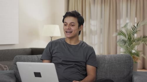 Cheerful Man Video Chatting on Laptop at Home