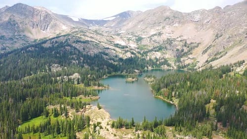 Drohnen-Luftaufnahmen des wunderschönen Rocky Mountain Lake mit klarem blauem Wasser, umgeben von Mountain P