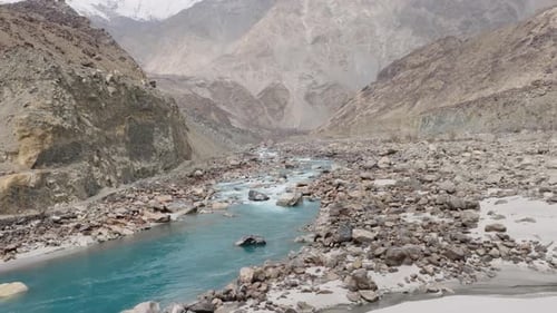 Aerial View of a Pristine River Flowing Through a Rugged Mountain Range in Pakistan Highlighting the