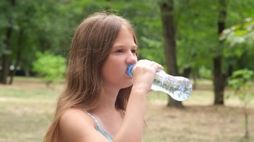 Girl Drinking Water Bottle in a Green Park