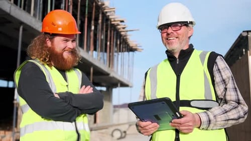 Los ingenieros del equipo y el constructor sonríen sosteniendo un plano en una tableta digital, en cámara lenta.