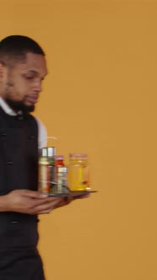 Young Adult Carries Tray of Sauces and Condiments