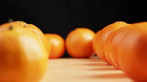 Camera movement along tangerines on a black background.