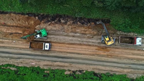 Luftbild von oben nach unten über Straßenbaumaschinen und Lastwagen