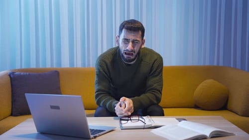 Young Adult Man Sits on Couch and Cries