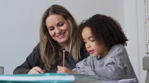 Caucasian Mother and African American Daughter Studying at Home Doing Homework in Cosy White Room