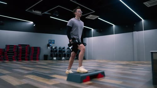 Fitness man trains with dumbbells in a modern gym, arm training slow motion