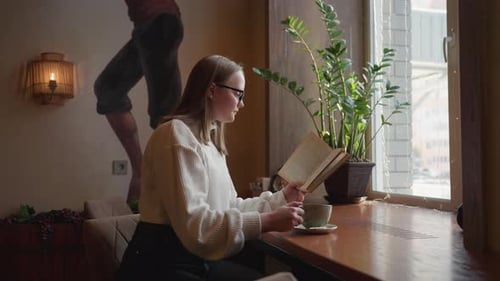 Woman Reading and Drinking Coffee in Cafe