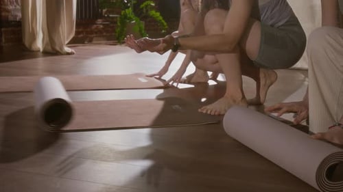 Three Female Yoga Practitioners Rolling Out Mats to Begin Lesson in Studio