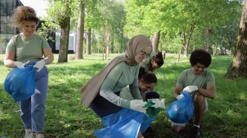 Multiethnic group of volunteers with garbage bags cleaning city park.