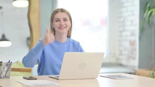 Woman Giving Thumbs Up at Desk with Laptop