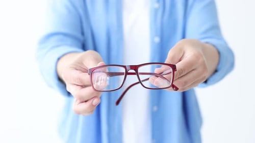 Woman showing pair of glasses on white background, closeup