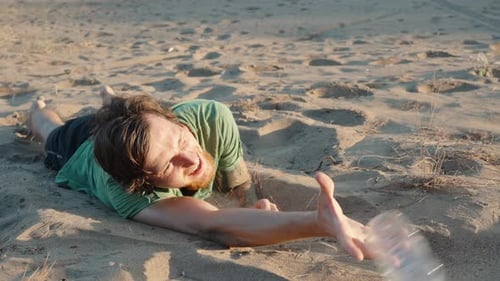 Un homme est allongé sur le sable sous le soleil brûlant du désert. Il sort sa main