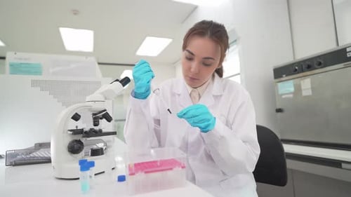 Focused young woman using microscope in laboratory
