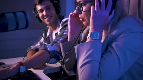 Young woman and man editing audio podcast in their studio.