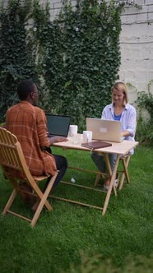 Two young entrepreneurs are working on their laptops in a garden