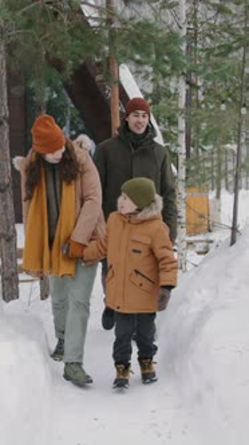 Young Family with Son Going on Walk in Winter Forest