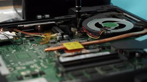 Screwdriver Repairing Motherboard Inside of Open Laptop