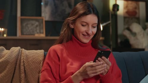 Smiling Woman Using Smartphone on Couch at Home