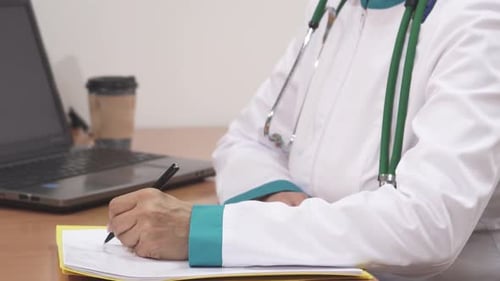 Close Up of a Joyful Female Doctor Diligently Filling Out Medical Papers at Her Desk