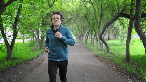 Sportive young man running. Young man runs in the park during the day