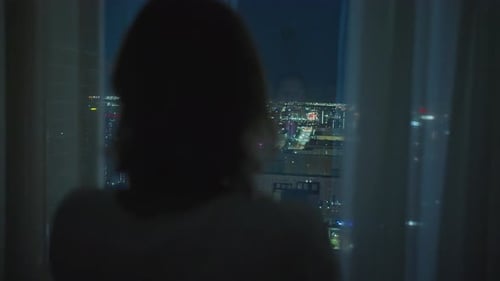 Woman Looking Out at City Lights at Night