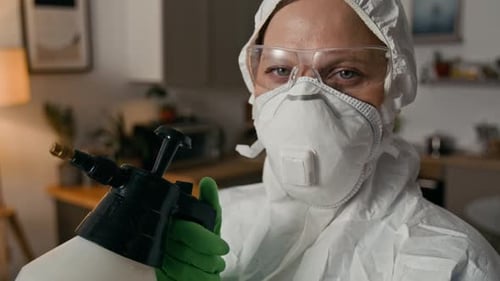 Adult in Protective Suit Holding a Spray Bottle