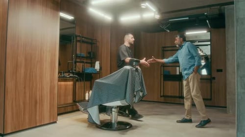 Young Barber Greeting Mature Male Customer Arriving for Appointment