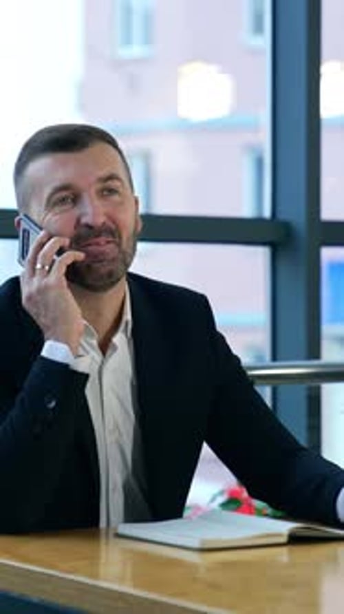 Successful businessman answering the phone in his office. Business talk in spacious light office.