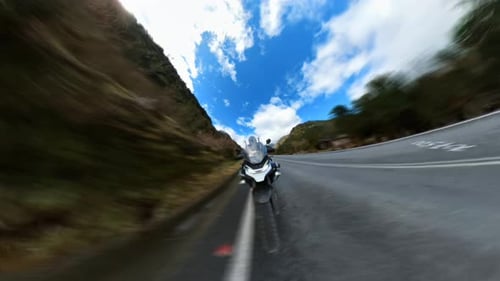 Hyperlapse of a motorcycle riding on a paved rural road surrounded by native forest on a beautiful s