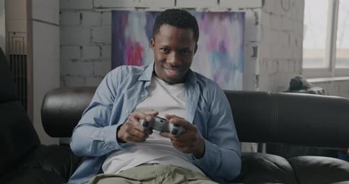 Young Man Playing Video Game on Couch Indoors