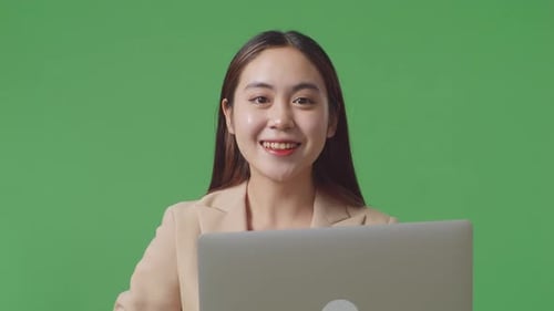 Close Up Of Asian Business Woman Using Laptop Computer And Smiling To Camera On Green Screen Studio