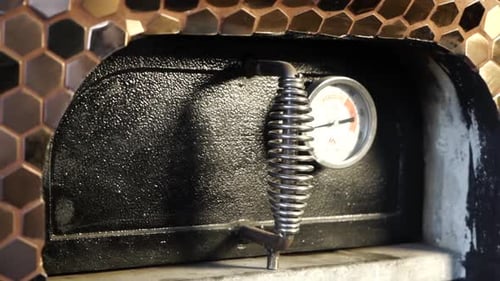 Revealing shot of an oven being opened with food wrapped in tinfoil cooking