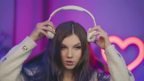 Young Woman Puts on Headphones in Pink Room