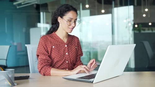 Happy young businesswoman finished work on laptop sitting at workplace in office. Smiling satisfied