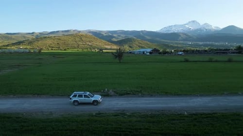 Car Driving on Dirt Road Through Rural Landscape