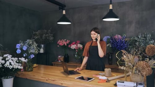 Seller the Owner of a Flower Shop Talks to the Customer on the Phone and Takes an Order for a