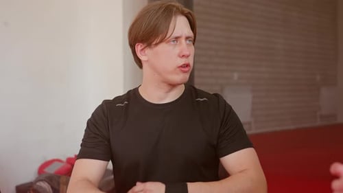 Athlete in Black Sportswear Prepares Hand Wrap Before Training on Red Mat in Gym