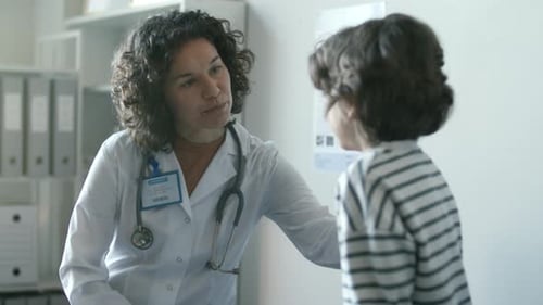 Positive Female Doctor Talking to Little Boy during Medical Check-Up at Clinic
