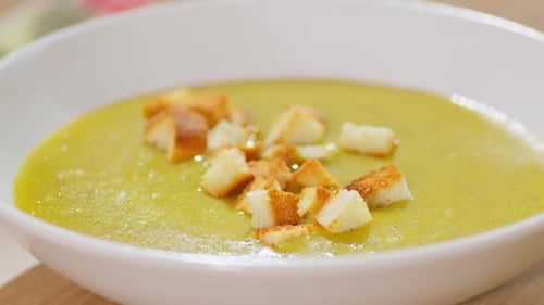In a Close Up Pieces of Dried White Bread Fall Into the Thick Soup