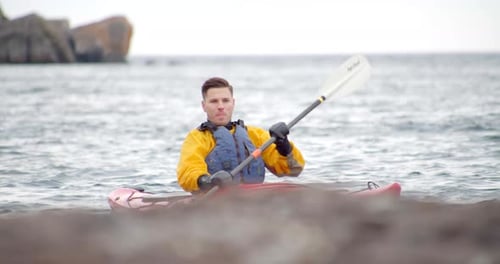 Single man kayaking on a mountain lake view through the trees on a sunny day
