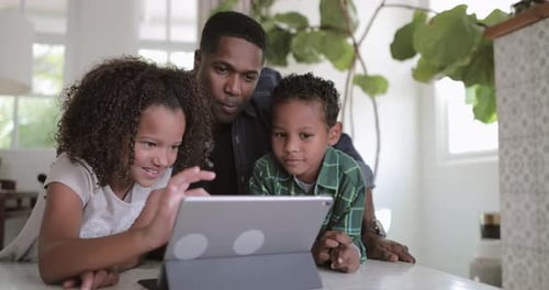 Father and Children Using Tablet Device in Kitchen