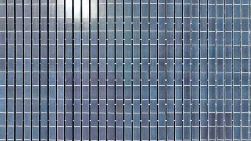 Aligned Array Of Solar Panels On Building Rooftop. Renewable Energy. aerial topdown, pullback ascend